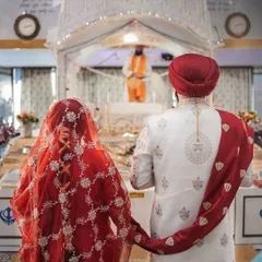 A powerful image from behind the couple as they stand before the Guru Granth Sahib. This shot captures the reverence and significance of the Anand Karaj ceremony.