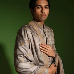 My steel grey raw silk sherwani is an ideal choice for a groom seeking a sophisticated and modern color palette. The ensemble includes a matching stole with detailed borders, adding a layer of elegance.