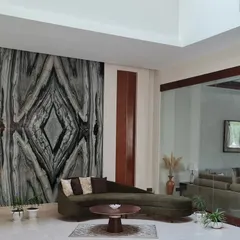 A book-matched marble slab serves as a dramatic art piece in this living area. The natural, symmetrical pattern of the stone creates a powerful focal point, balanced by the room's minimalist furniture and earthy tones.