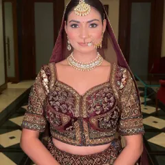 A portrait of a bride exuding grace. This subtle bridal makeup look focuses on defined eyes and a soft lip color, complementing her intricate velvet lehenga.