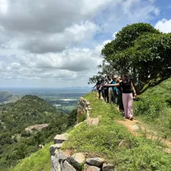 A team of bankers walking along the historic fort wall on the Makalidurga trail. The path offers a mix of natural beauty and historical intrigue, making it a popular choice for a one-day corporate outing.