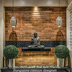 A tranquil corner featuring a Buddha statue set against an exposed brick wall. The hanging pendant lights and minimalist shelf create a peaceful and meditative focal point in the home.