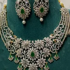 A delicate diamond-look choker with intricate floral patterns and green stone drops. This is a great option for a modern, elegant look for a reception or cocktail party.