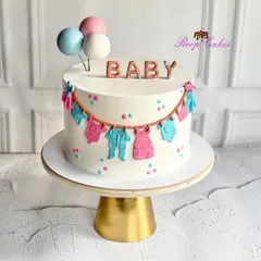 A sweet celebration for the tiniest bundle of joy. This adorable baby shower cake is decorated with a clothesline of fondant baby clothes, pastel polka dots, and balloon toppers.