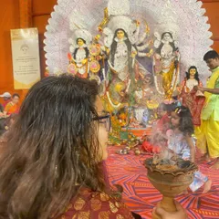 A mother and child participating in a Dhunuchi Naach ceremony during Durga Puja. This is a great example of event photography, capturing cultural traditions and family moments together.