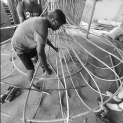 An artisan carefully works on the intricate cane structure of the Biergarten light. This collaborative process, combining our design with their traditional techniques, is central to how we bring soul into our projects.