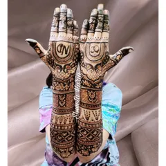 A full view of an intricate engagement mehendi design. The palms feature the couple's initials 'N' and 'D' and a motif of interlocking rings, symbolizing their union.