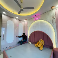 A dream room for a little one. We designed this baby pink kids' room with a custom arched headboard, a full-height sliding wardrobe for ample storage, and fun neon lighting to create a space that is both playful and practical.