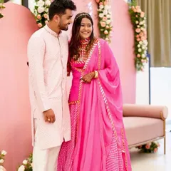 A full-length view of the happy couple. The vibrant pink of the bride's outfit and the groom's matching kurta create a perfect picture for any wedding event.