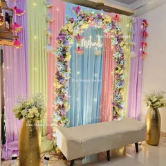 This pastel Mehendi setup creates a dreamy and modern aesthetic for your celebration. We use a soft palette of pastel drapes, a beautiful floral arch, hanging decor elements, and a custom 'Mehndi' neon sign to bring this vision to life.