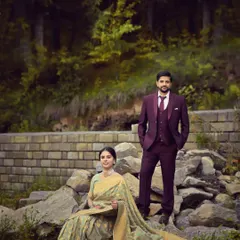 An elegant pre-wedding portrait set against the rocky, green terrain of the Himalayan foothills. The formal attire of the couple contrasts beautifully with the rugged nature, creating a sophisticated yet earthy vibe.