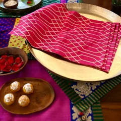 A pink brocade placemat from the same set, showcasing the beautiful geometric pattern and rich texture of the fabric.