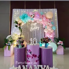 A beautiful pastel-themed decoration for a 10th birthday. The setup includes a curtain backdrop with fairy lights, a pastel balloon arch, floral arrangements, and light-up marquee letters.