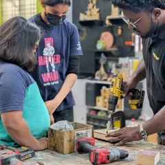 Our mentors are passionate about teaching the next generation. Here, a mentor helps a young maker use a drill safely, guiding her through the process of building her project.