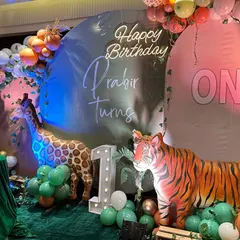 Another take on the popular jungle theme, this setup for Prabir's first birthday includes a tiger, giraffe, and zebra, all set against a backdrop with a custom neon birthday wish.