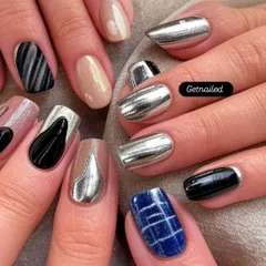 This set showcases a variety of chrome and metallic designs on each nail. From solid silver chrome to abstract black and silver patterns, it's a great example of a customized, edgy look.