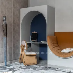This multifunctional activity room features a cozy reading nook built into an arched structure. The deep navy backdrop and unique chair create an inviting space for reading, working, or simply relaxing.