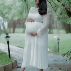 This shot captures the beautiful silhouette of pregnancy. The mother cradles her belly, creating a classic and timeless maternity portrait.