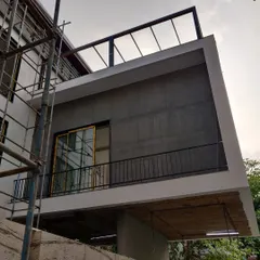 The "before" shot, showing the same residential facade during the construction phase with exposed concrete and scaffolding.