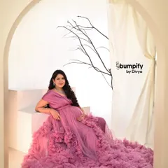 A vision in pink. This mom-to-be is wearing a magnificent ruffled tulle gown that fills the frame, creating a soft, dreamy, and utterly glamorous maternity portrait.