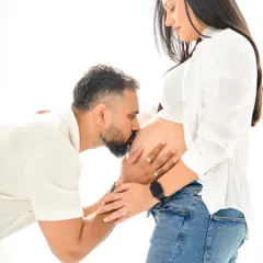 Sometimes the simplest moments are the most powerful. This intimate, minimalist portrait captures a dad-to-be kissing the baby bump, showcasing the deep connection and anticipation in a casual, comfortable setting with just jeans and a white shirt.