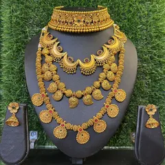 A beautiful gold-finish set featuring a choker, a mid-length necklace with a mango design, and a longer coin necklace.