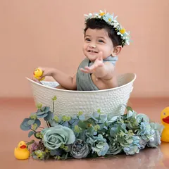 A happy little one waving from the tub, surrounded by rubber ducks and flowers. A classic and adorable tub bath moment.