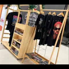 A custom wooden kiosk designed for a fashion brand, featuring clothing racks and shelving. This type of open, minimalist stall is perfect for pop-up shops in malls and exhibitions.