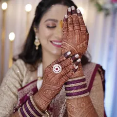 A happy client showing off her gorgeous, dark engagement mehendi stain. The color beautifully complements her outfit and jewelry.