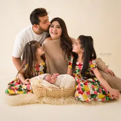 A portrait of adoration. The whole family gathers around the newborn, with older sisters looking on with love and wonder.