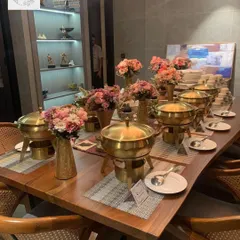 We transform any space into an elegant dining area. This is a glimpse of our classic buffet setup for an intimate corporate gathering, featuring our signature brass chafing dishes and coordinated floral arrangements.