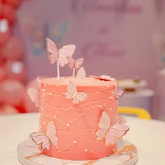 A close-up of the beautiful butterfly-themed birthday cake. The soft pink frosting, delicate wafer butterflies, and pearl sprinkles create a dreamy look for a special celebration.
