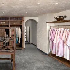The main retail area at Eka features custom-designed wooden wardrobes and a unique glass display case for accessories. The arched doorway and lime-washed walls add to the feeling of being in a familiar, personal space rather than a conventional store.