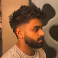 A textured haircut with a low fade and a sharp beard lineup. This style has great movement and a clean finish.