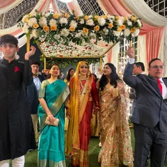 A beautiful Kashmiri bride making her entrance under a phoolon ki chaadar. The canopy is elegantly decorated with white and peach flowers, held by her loved ones.
