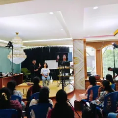 A wide shot of a makeup masterclass in session. Students are seated with a clear view of the stage, where I am performing a live demonstration on a model. An attentive class is the best sign of effective teaching.