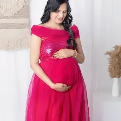 Capturing the simple, loving gesture of a mother holding her belly. This pose is so natural and full of emotion. The off-shoulder magenta gown adds a touch of elegance to the portrait.