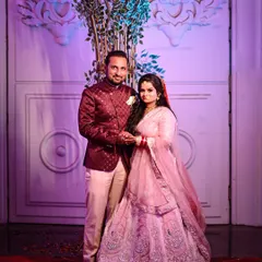 A classic posed portrait of the couple on their wedding day. Dressed in beautiful pink and maroon outfits, this shot captures their elegance and happiness against the backdrop of their wedding decor.