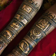 A close-up of a Maharashtrian bridal forearm design. It features auspicious symbols in separate blocks, including a kalash, diyas, a peacock, and Lord Ganesha, along with the phrase 'Shubh Vivah' (Happy Wedding).