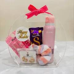A lovely Rakhi hamper for a sister, filled with self-care goodies. It includes a body spray, earrings, a lip balm, a soft scrunchie, and Dairy Milk Silk, all packed in a cute acrylic bag.
