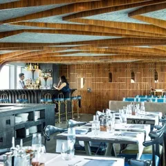The main dining hall of the Queensline Sea Yah floating restaurant. To address the challenge of a low ceiling, we developed a repeating, tree-like structural element from Indian Teak wood, which gives the long space character and a sense of rhythm.