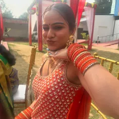 A happy client taking a selfie at a wedding, looking radiant in an orange suit and my statement gold jhumkas.