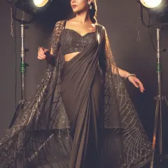 Where contemporary meets tradition, the cape saree steals the spotlight. This grey-brown version features a long, flowing cape with intricate web-like embroidery.