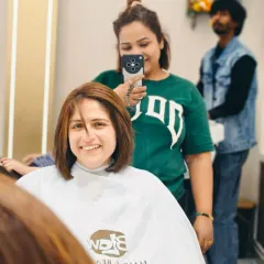 A mirror selfie with a client, showing off her new look. You can see our salon's cape and branding in the reflection.
