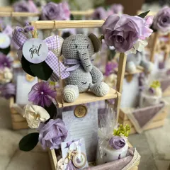 Welcoming a baby girl with a touch of handmade charm. This custom announcement hamper, in a lovely lavender theme, features a hand-crocheted elephant toy, a personalized announcement card, and other delicate keepsakes.