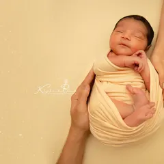 A warm, golden-toned version of the "in your hands" pose. This simple, elegant setup creates a feeling of warmth and security, focusing on the delicate features of the newborn.