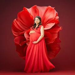 A bold and passionate portrait using a vibrant red gown and fabric art. The color red symbolizes love and life, making it a powerful choice for a dramatic maternity photo.