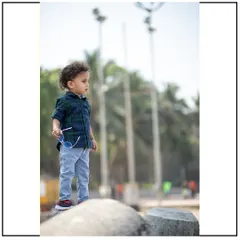 A candid, full-body shot of a toddler standing on the rocks. His casual stance and plaid shirt give this kids' photoshoot a stylish, modern feel.
