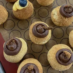 A close-up of our choux pastries, showing the different fillings. We offer a variety, including chocolate, blueberry, and lemon curd, each with a crispy craquelin top.