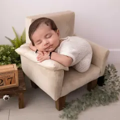 The peaceful, sleepy moments of a newborn are so precious. In my studio, I create a calm and safe space to pose your little one, focusing on capturing their serene innocence and tiny details, like this sweet baby dreaming on a miniature armchair.